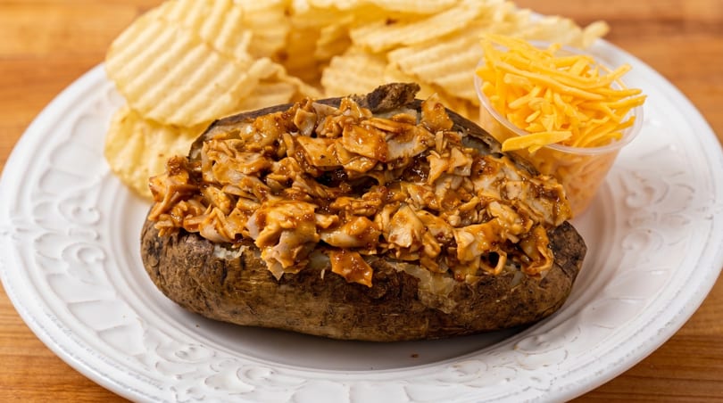 Baked potato topped with BBQ chicken, served with ruffled potato chips and shredded cheddar cheese.